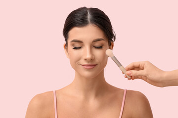 Fototapeta premium Beautiful young woman and female hand with makeup brush on pink background