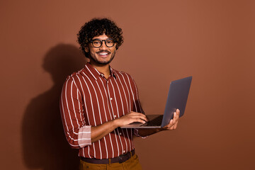 Photo of nice young man use laptop wear striped shirt isolated on brown color background