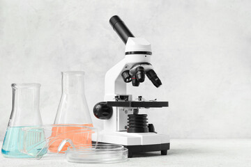 Microscope and laboratory glassware on light background