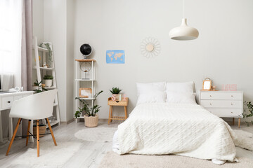 Interior of light teenager's room with bed, shelf units and study table