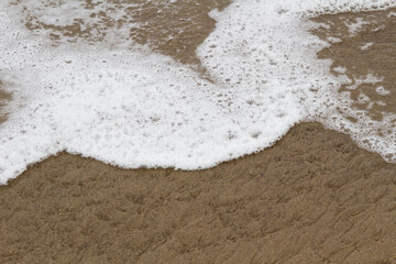 Tight Shot Of White Sea Foam On Sand Beach From Ocean Wave