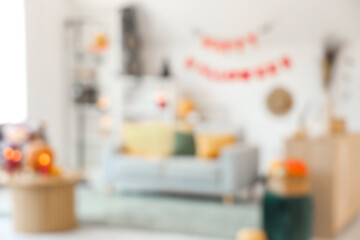 Blurred view of light living room decorated for Halloween with sofa, table and shelf unit