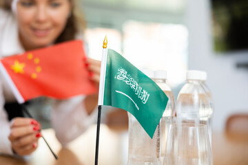 Little flag of Saudi Arabia on table with bottles of water and flag of China put next to it by...