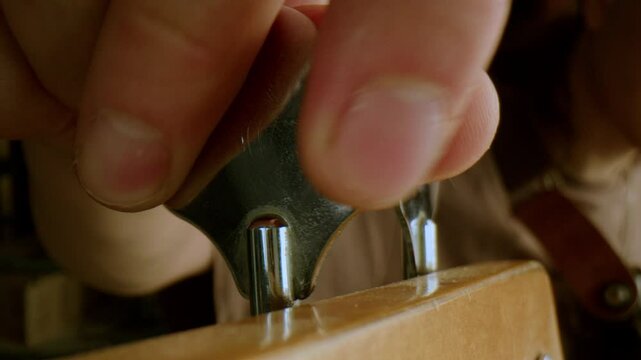 Hand of unrecognizable male musician adjusting tuning peg on guitar before playing. Close-up view