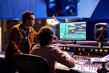 Post production team working on editing sound settings in studio, audio software interface on...