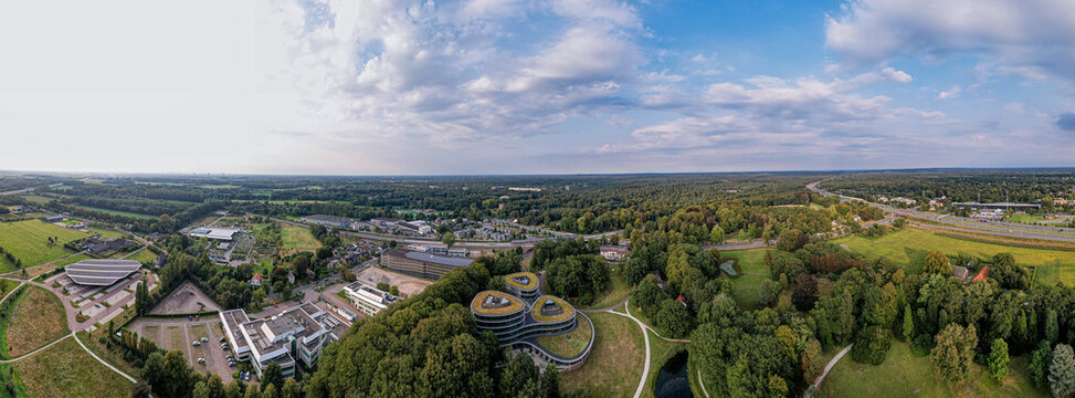 Super wide panorama of Triodos bank in green park surrounding of Driebergen Zeist with train station and highway in the background