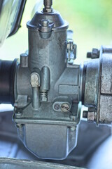 detail on old motorcycle made of grey iron carburetor on street