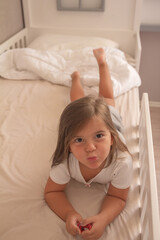 the little girl playing and tickling on the bed and having fun