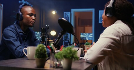 Woman radio show presenter having live conversation with man, enjoying cup of coffee together,...
