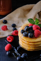 pancakes with berries and honey on dark background