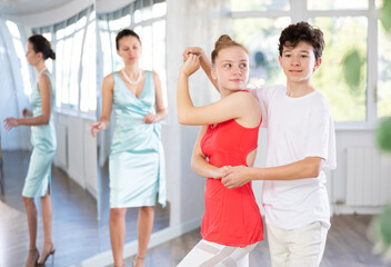 Positive girl and boy dancing slow ballroom dance in choreography studio