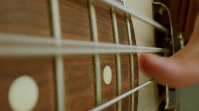 Fingers of guitarist plucking strings on wooden fret as playing live music. Extreme close-up view