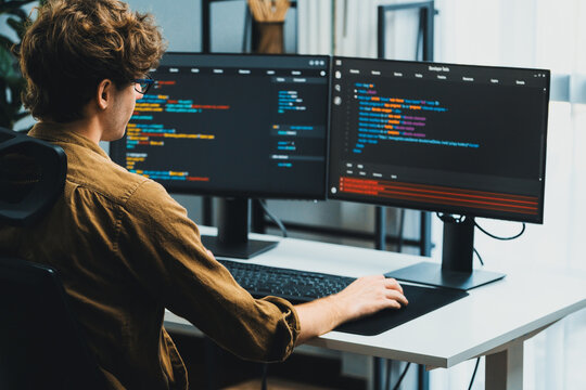 IT developer working online software development on pc monitors at modern home office on coding application screens, creating updated latest program firmware information version concept. Gusher.