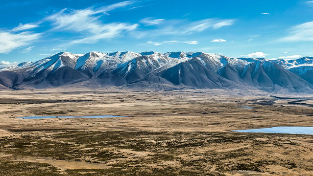 The way to Lake Ohau and the southern alps through alpine grasses and tundra terrain