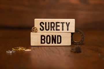 Text SURETY BOND is written on a notebook with a pen and a magnifying glass lying on the table.