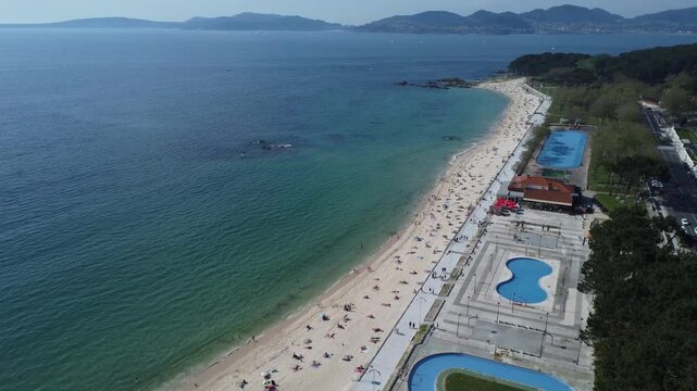 Aerial view of Playa de Samil, the main beach of Vigo in Galicia in northwest Spain. Sunny day, crystal clear blue sea. Houses, streets. Drone take.