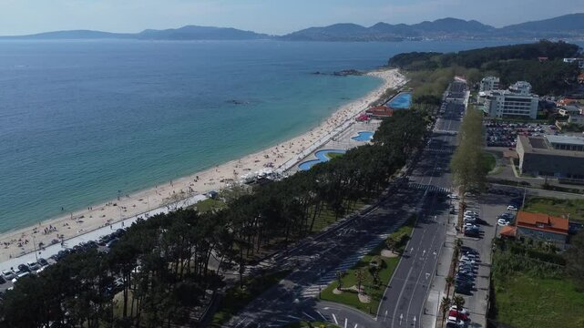 Aerial view of Playa de Samil, the main beach of Vigo in Galicia in northwest Spain. Sunny day, crystal clear blue sea. Houses, streets. Drone take.