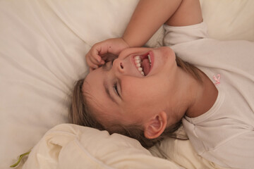 the little girl playing and tickling on the bed and having fun