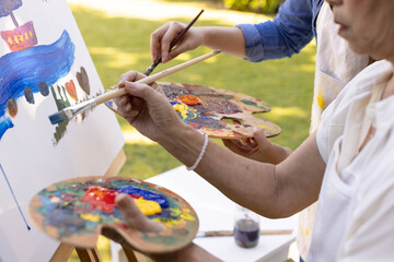 Naklejka premium Painting on canvas, two people holding palettes and brushes outdoors