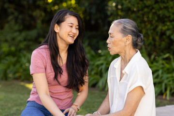 Talking and smiling, asian woman enjoying outdoor conversation with asian grandmother