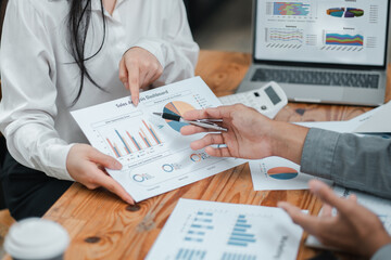 Business professionals reviewing sales analytics and performance metrics on paper and digital devices in a collaborative office environment.