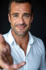Obraz premium Professional Man in Formal Attire Offering Help with a Gentle Smile Against a Black Background