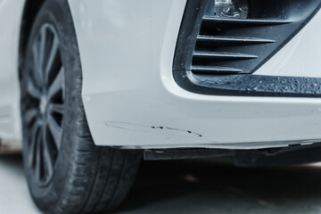 A close-up shot of a scratched sedan highlights the imperfections on its surface, with deep...