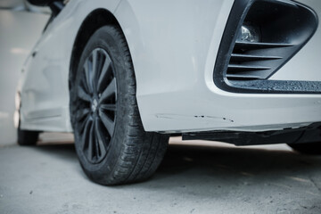 A close-up shot of a scratched sedan highlights the imperfections on its surface, with deep scratches and scuffs on the paint, revealing the wear and tear from frequent use.