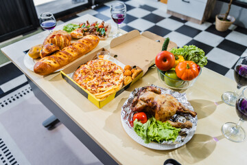 A business office is set for a Halloween party, with food spread across a desk pizza, bread, chicken grill, French fries, salad, and beer ready for celebration, but no people present.