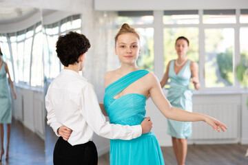Fototapeta premium Dance teacher teaches a girl and boy couples ballroom dancing