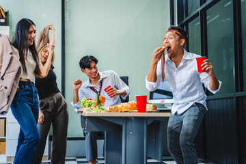 Asian office colleagues and friends enjoy a daytime BBQ with pizza and beer, celebrating Halloween and cheering for their favorite soccer team, creating a lively atmosphere filled with joy.