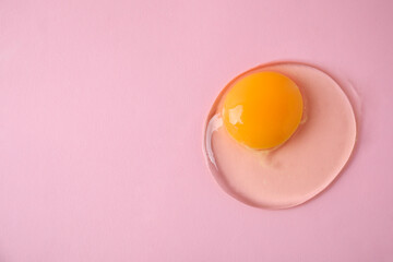 One raw egg on pink background, top view. Space for text