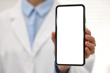 Doctor showing smartphone with blank screen in hospital, selective focus