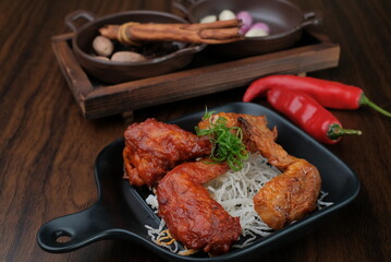 Fried chicken wings. Chicken wings on a wood background. Barbecue meat, grill. Sauce in bowls, ketchup, mayonnaise, mustard, cheese sauce. Appetizing fried meat in the black plate