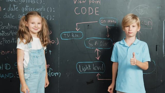 Caucasian girl writing blackboard with engineering prompt or coding, programing system written in STEM technology classroom and turnaround to looking at camera while boy showing thumb. Erudition.