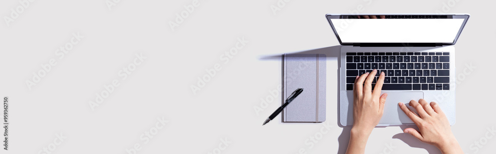 Wall mural person using a laptop computer with a notebook - flat lay