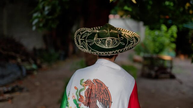 mexican man wearing a mariachi hat and covered by a flag of Mexico