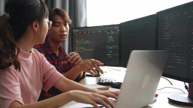 Slow motion back end software developer engineer for computer programming working together on debugging writing computing code, solving complex algorithms display on monitor in office. Burgeoning