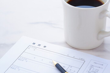 コーヒーを飲みながら、履歴書を書く
