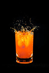 Water splash from orange juice glass on black background