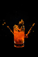 Water splash from orange juice glass on black background