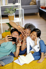 Portrait Of Happy Asian Family Selfie Using Smartphone With Posing Heart Sign