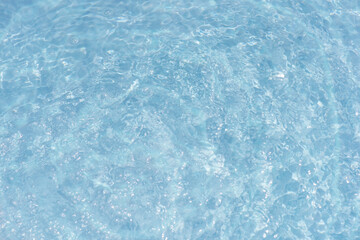 Obraz premium Blue water with ripples on the surface. Defocus blurred transparent blue colored clear calm water surface texture with splashes and bubbles. Water waves with shining pattern texture background.
