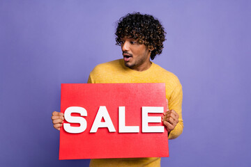Photo of excited positive man wear trendy yellow clothes arms hold red placard sale empty space...