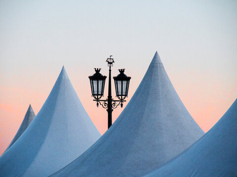 Portugal, Lisbon. Street lamp and top of artist tents at dusk in Commerce Square (Praca do Comercio).
