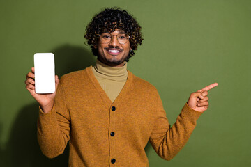 Photo of handsome young guy hold device white screen point empty space dressed stylish brown garment isolated on khaki color background