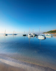 Obraz premium Crystal clear waters with boats anchored near a tropical beach