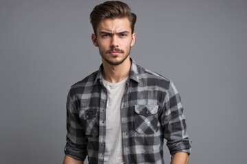 Obraz premium Young man with serious expression wearing plaid shirt against gray background