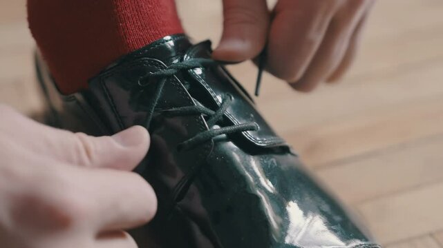 Man Lacing Shiny Leather Shoe | Closeup of Hands Tying Formal Footwear | Red Sock and Polished Oxford on Light Parquet Floor | Businessman Preparing | Elegant Male Fashion Detail Shot