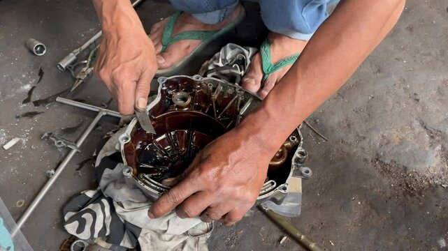 a mechanic is removing a gasket attached to the engine block using a cutter blade